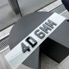 A 4D 6mm number plate with raised black acrylic characters on a white plate, resting on a dark, circular table.