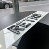 An angled close-up of a 'RETRO' number plate, showcasing the raised, glossy black characters against a blurred street background.
