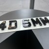 An angled view of a 4D 6mm number plate, showing the raised, laser-cut acrylic characters on a white plate.